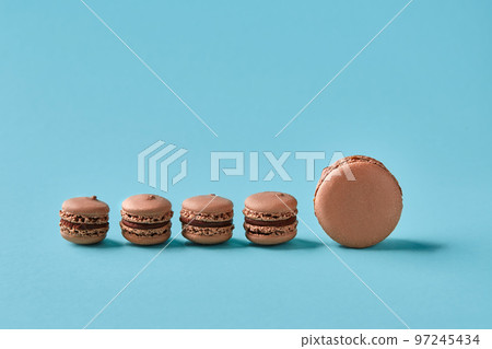 Close-up studio shot of tasty chocolate macarons on blue background. 97245434