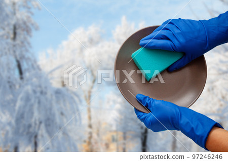 Women's hands in protective gloves with sponge and plate with winter on background. Women's hands in protective gloves with sponge and plate with winter on background. 97246246