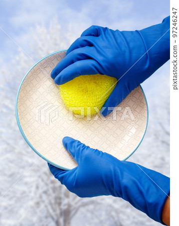 Women's hands in protective gloves with sponge and plate with winter on background. Women's hands in protective gloves with sponge and plate with winter on background. 97246247