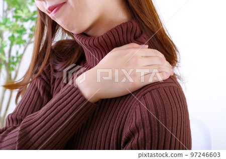 A young woman who puts her hand on her shoulder so that it hurts A young woman who puts her hand on her shoulder so that it hurts 97246603