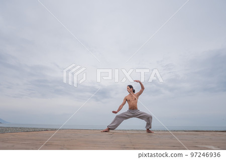 Caucasian man practices martial arts outdoors. balance and meditation. Caucasian man practices martial arts outdoors. balance and meditation. 97246936