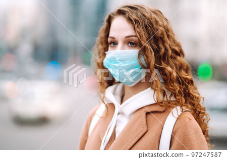 Woman in protective medical mask on her face on the street. Woman, wear face mask. Corona virus. Woman in protective medical mask on her face on the street. Woman, wear face mask. Corona virus. 97247587