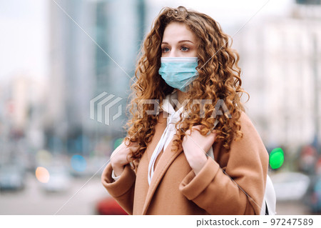 Woman in protective medical mask on her face on the street. Woman, wear face mask. Corona virus. Woman in protective medical mask on her face on the street. Woman, wear face mask. Corona virus. 97247589
