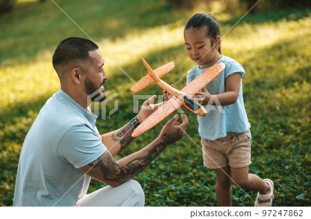 Young man showing his kid how to play with the toy plane Young man showing his kid how to play with the toy plane 97247862