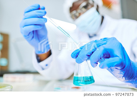Black scientist taking liquid samples with pipette in laboratory Black scientist taking liquid samples with pipette in laboratory 97247873