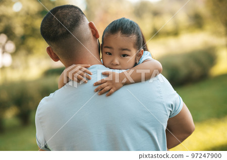Young man holding his daughter while spending time in the park Young man holding his daughter while spending time in the park 97247900