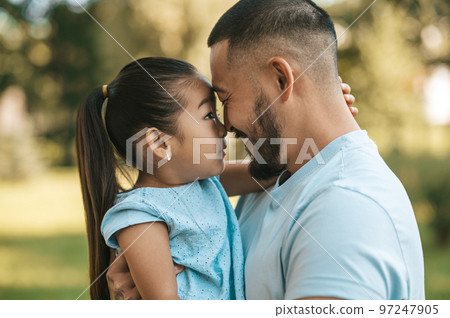 Young man holding his daughter while spending time in the park 97247905