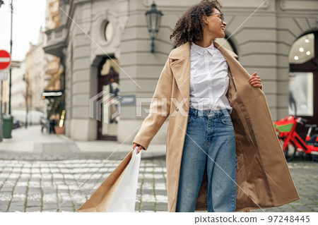 Fashion afro american woman after successful shopping with paper bags crosses the road in city Fashion afro american woman after successful shopping with paper bags crosses the road in city 97248445