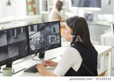 Young woman looking at surveillance camera feeds in security office Young woman looking at surveillance camera feeds in security office 97248542