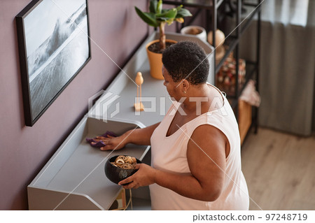 Senior woman dusting shelves Senior woman dusting shelves 97248719