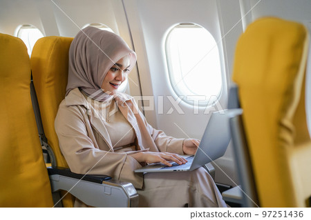 Beautiful asian muslim business woman working on digital laptop computer during the flight for her business trip. Business and transportation concept 97251436