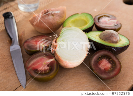 vegetables black tomatoes, avocado and onions on wooden board vegetables black tomatoes, avocado and onions on wooden board 97252576