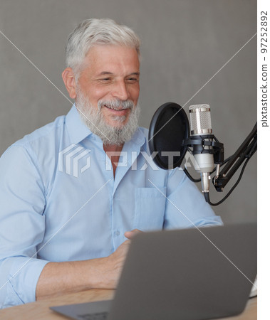 older man with gray hair irecording podcast in recording studio with microphone and headphones older man with gray hair irecording podcast in recording studio with microphone and headphones 97252892