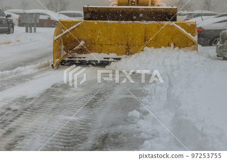 Winter snowstorm with snow blizzards causing of snow to be cleaned up tractor during storm Winter snowstorm with snow blizzards causing of snow to be cleaned up tractor during storm 97253755