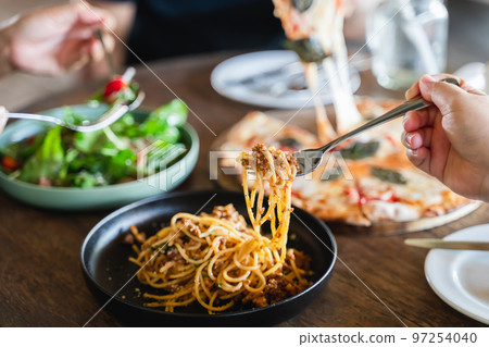 Family or friends eating food together. people eating Italian food Pasta, Pizza, Salad on the table. Family or friends eating food together. people eating Italian food Pasta, Pizza, Salad on the table. 97254040