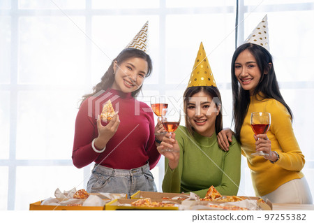 Group of Asian friends gather to celebrate Christmas with champagne and eating pizza at home. Joy of holiday party with friends or colleague concept 97255382