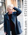 Fashionable blonde woman walking exploring the city. 97255549