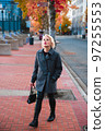 Fashionable blonde woman walking exploring the city. 97255553