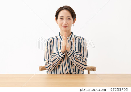 A woman sitting on a chair and putting her hands together 97255705