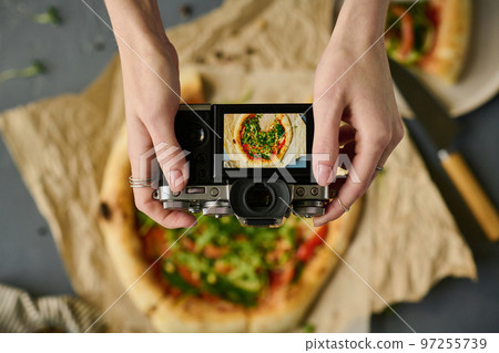 High angle view of woman taking photo of homemade pizza with digital camera 97255739