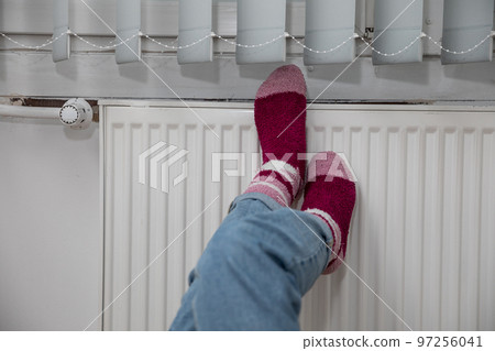 Warming cold feet on a hot radiator. Thick wool socks. Warming cold feet on a hot radiator. Thick wool socks. 97256041