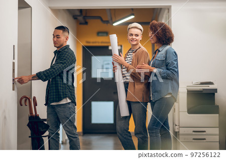 Group of three office workers waiting for the lift 97256122
