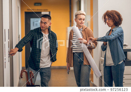 Three company employees standing at the elevator door Three company employees standing at the elevator door 97256123