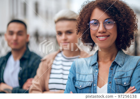 Smiling joyous woman in spectacles and her friends outdoors 97256138