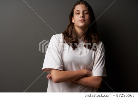 Closeup portrait of casual natural girl wearing white t-shirt looking confident Closeup portrait of casual natural girl wearing white t-shirt looking confident 97256565