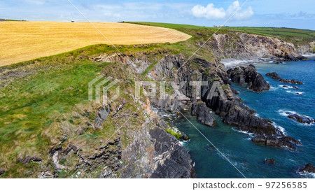 Farm fields on the shore of the Celtic Sea, south of Ireland, County Cork. Beautiful coastal area. Turquoise waters of the Atlantic. Picturesque stone hills. Drone point of view. 97256585