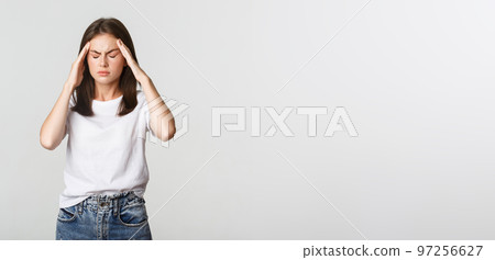 Portrait of dizzy or sick woman touching head and grimacing from pain, having headache, suffering migraine 97256627