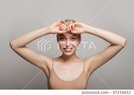 Close up of young woman holding her arms up and showing her armpit on white background. Close up of young woman holding her arms up and showing her armpit on white background. 97256652