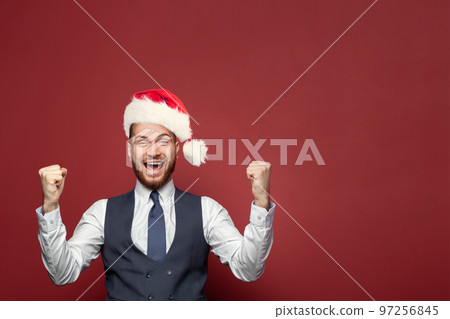 Happy excited businessman in Christmas hat laughing on red banner background portrait. Happy excited businessman in Christmas hat laughing on red banner background portrait. 97256845