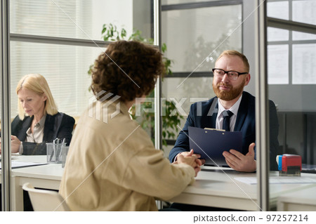 Portrait of smiling male consultant talking to woman in cubicle at agency office 97257214