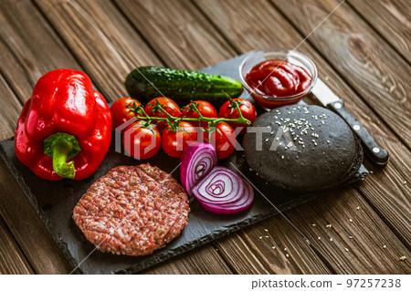 Top view of ingredients for beef black burger on a black stone board with knife. Delicious food Top view of ingredients for beef black burger on a black stone board with knife. Delicious food 97257238