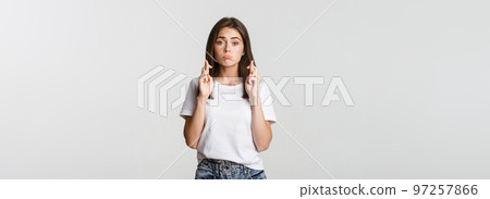 Hopeful cute brunette girl cross fingers good luck, making wish or praying Hopeful cute brunette girl cross fingers good luck, making wish or praying 97257866