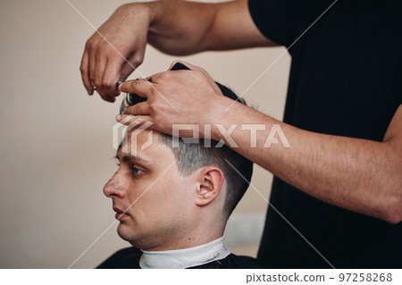 hairdresser does haircut for man in barber shop 97258268