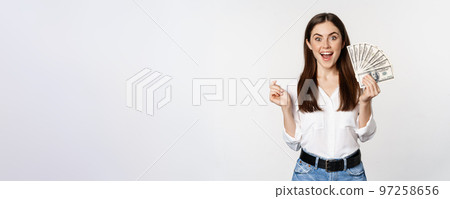 Enthusiastic woman showing money, cash and smiling, got loan, micro credit, standing delighted against white background 97258656