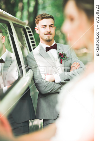Happy newlywed couple, man and wife kissing near stylish retro car 97259223