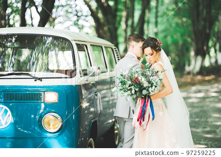 Happy newlywed couple, man and wife kissing near stylish retro car 97259225