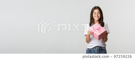 Happy cute young birthday girl, smiling and looking at b-day gift 97259226