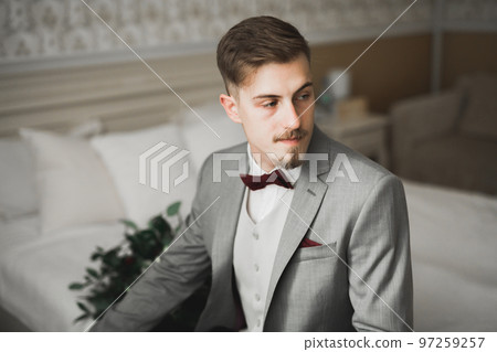 Grooms morning preparation. Handsome man getting dressed and preparing for the wedding Grooms morning preparation. Handsome man getting dressed and preparing for the wedding 97259257