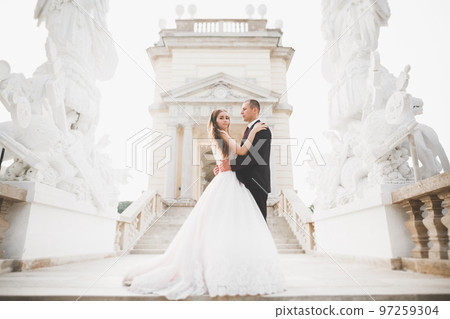 Beautiful bride and groom embracing and kissing on their wedding day outdoors 97259304