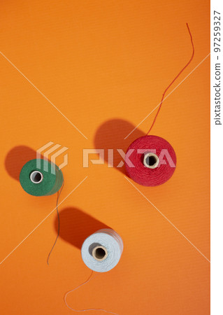 Three coils with colored threads on a colored background 97259327