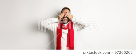 Christmas concept. Happy man close his eyes and waiting for gifts, smiling excited, celebrating new year, winter holidays, standing over white background Christmas concept. Happy man close his eyes and waiting for gifts, smiling excited, celebrating new year, winter holidays, standing over white background 97260203