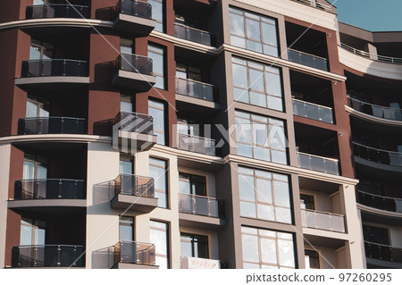 Modern apartment complex against pale sky. Construction, investment in real estate, buying housing on real estate market concept. Cityscape view. High-rise brown and white building, panoramic windows. Modern apartment complex against pale sky. Construction, investment in real estate, buying housing on real estate market concept. Cityscape view. High-rise brown and white building, panoramic windows. 97260295