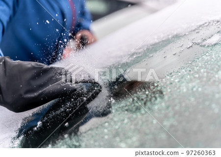 man uses ice scrapers to thaw car windshield man uses ice scrapers to thaw car windshield 97260363