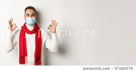 Covid-19, lockdown and quarantine concept. Satisfied handsome guy in face mask showing okay sign, approve or agree, like something, white background Covid-19, lockdown and quarantine concept. Satisfied handsome guy in face mask showing okay sign, approve or agree, like something, white background 97260379