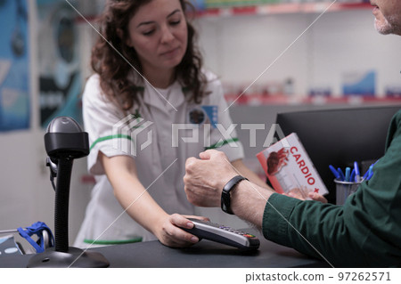 Elderly client paying cardiology pills with modern watch using terminal for contactless payment in drugstore. Customer buying pharmaceutical treatment to curse disease. Health care support 97262571