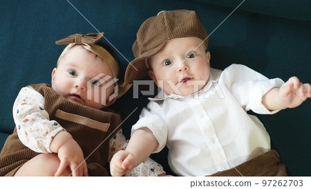 twin babies in retro clothes. brother and sister a twins kids sit on the couch in retro clothes cap play among lifestyle themselves. happy family kid dream twin concept twin babies in retro clothes. brother and sister a twins kids sit on the couch in retro clothes cap play among lifestyle themselves. happy family kid dream twin concept 97262703